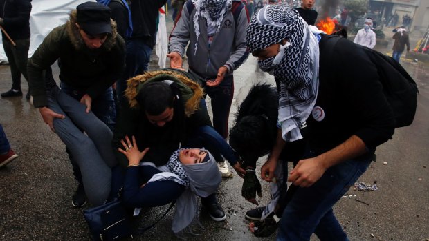 Protesters carry a girl who fainted after she inhaled tear gas fired by riot police during demonstrations in front of the US embassy in Aukar, east of Beirut, Lebanon.