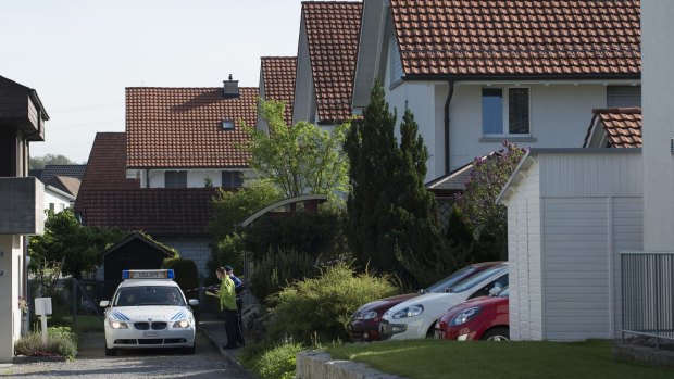 A police car stands in a residential area in Wuerenlingen, Switzerland, where police found five people dead.