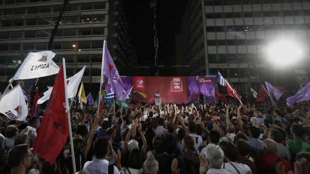 Syriza party supporters wave flags as Alexis Tsipras, former Greek prime minister, speaks in Athens on Friday