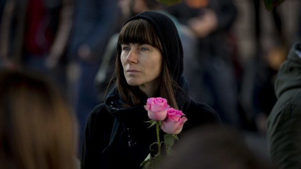 A woman holds roses while standing outside the Colectiv nightclub during a mourning march joined by thousands on Sunday.