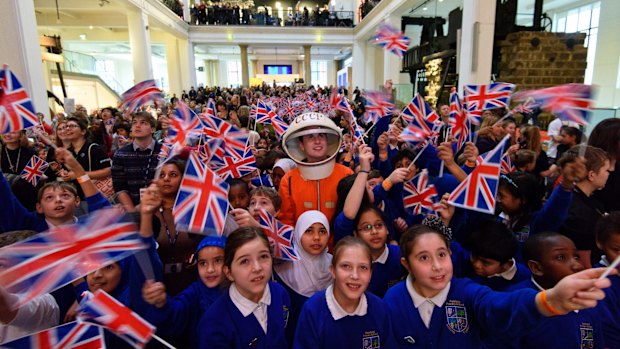 A man in a space suit watches a television with school children at the Science Museum ahead of the launch of the space mission from Baikonur Cosmodrome in Kazakhstan.