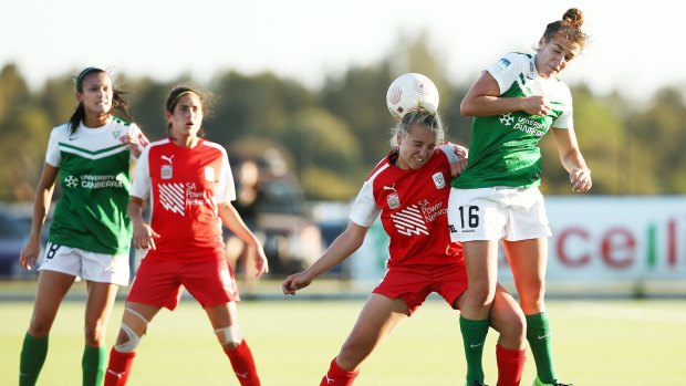 Grace Abbey of Adelaide competes with Canberra United's Tegan Riding for the ball.