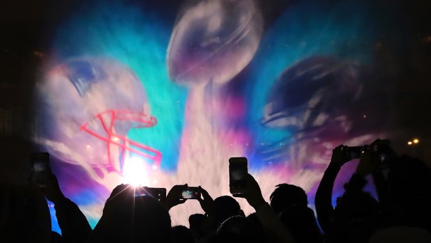 Colourful show: Football fans snap photos of the 3D light show projected on water at the Super Bowl Live event in Houston.