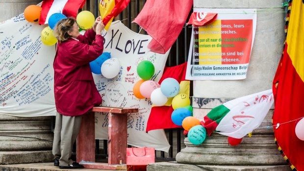 A woman attaches a message to a Spanish flag at a memorial in Place de la Bourse in Brussels on Sunday.