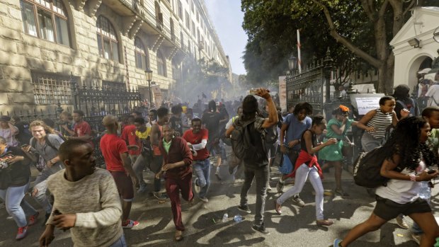 Protesting university students flee as police fire stun grenades .