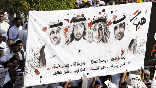 Shiite Muslims carry a banner showing images of Saudi men killed in the attack on a mosque in the eastern city of Dammam.