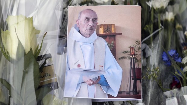 A picture of late Father Jacques Hamel is placed on flowers at the makeshift memorial in front of the city hall close to the church where he was killed. 