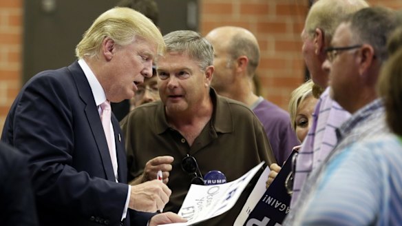 Trump signs autographs after speaking at a rally and picnic in Iowa.