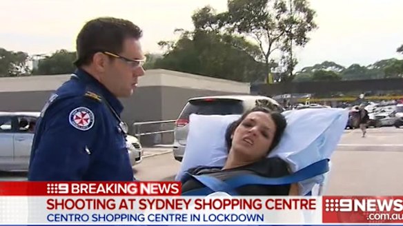 A woman is wheeled away by paramedics after the shooting at Bankstown Central Shopping Centre.