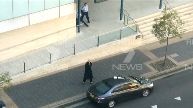 Farhad Khalil Mohammad Jabar, dressed in black, points his gun outside the Parramatta police station.