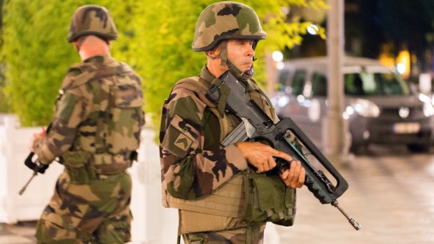 French soldiers stand guard by the sealed off area of an attack after a truck drove on to the sidewalk and ploughed through a crowd of revellers.