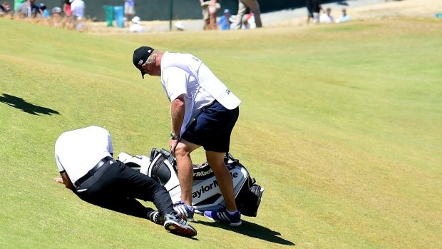 Jason Day is tended to by caddie Colin Swatton after collapsing on the ninth green.
