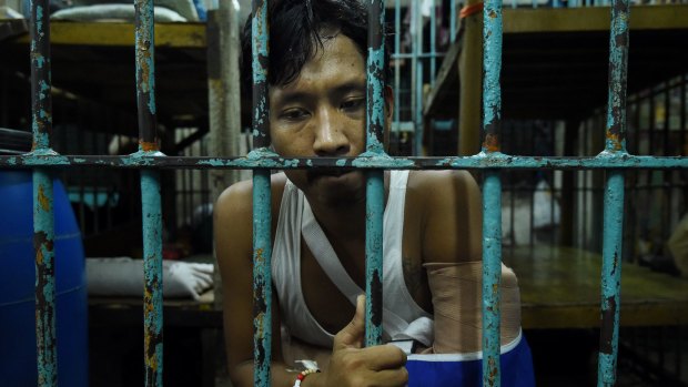 Wounded drug user Francisco Maneja, 27, sits in a cell at Manila Police Headquarters. 