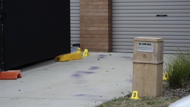 Forensic markers and purple spray paint on the driveway next to the Kambah home where a man was found dead on Wednesday. 