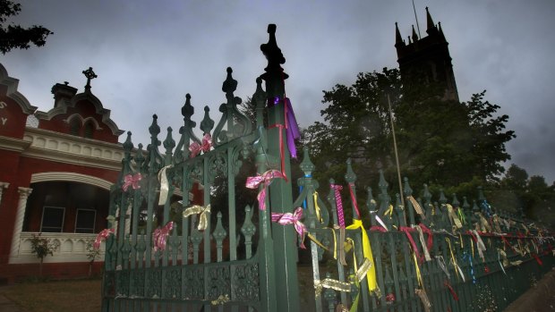 Ribbons tied to the fence at St Alipius Presbytery, church and old boys school in Ballarat pay tribute to the victims and survivors of child abuse. 