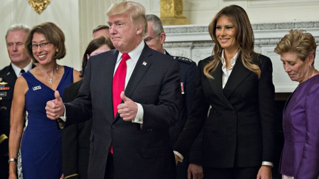 US President Donald Trump gives a thumbs up next to First Lady Melania Trump during an official photograph with senior military leaders and spouses in the State Dining room of the White House. 
