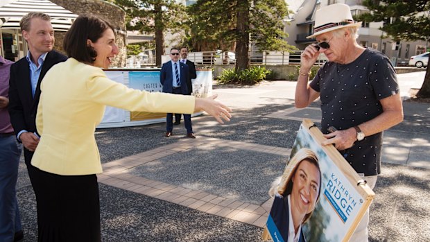 The Premier greets former independent Manly MP David Barr, who is holding a poster for independent candidate Kathryn Ridge.