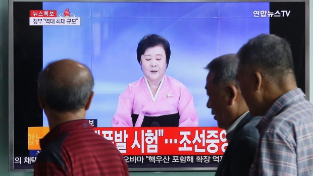 People pass by a TV screen showing a North Korean newsreader delivering a statement from the North's Nuclear Weapons Institute on Friday.