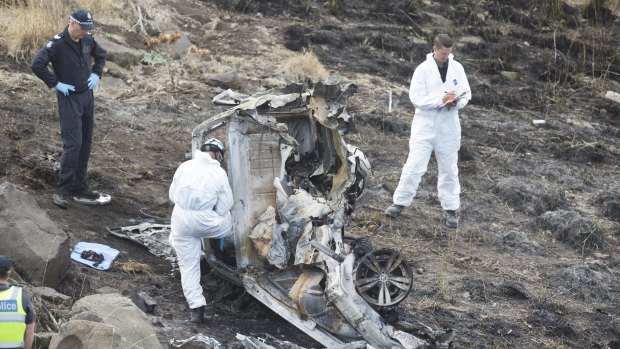 Police investigators pick over the wreckage of the car, which crashed 50 metres off the EJ Whitten Bridge in Melbourne after the driver lost control while racing against another car. 