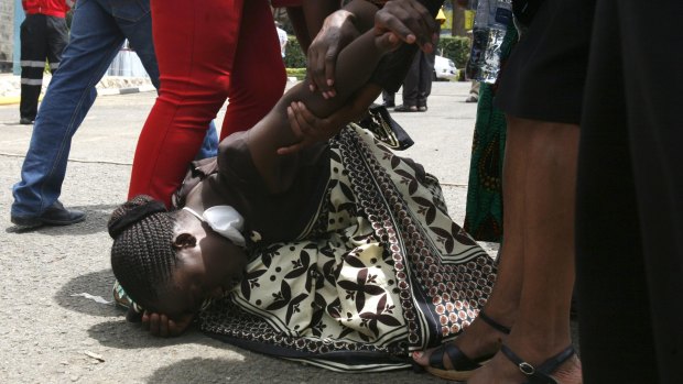 A relative is assisted by Kenya Red Cross staff as she reacts at the Chiromo Mortuary in Nairobi.