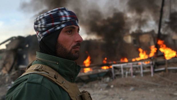 A Kurdish soldier passes by tyres set on fire by Islamic State militants to hinder airstrikes in Sinjar, Iraq. 