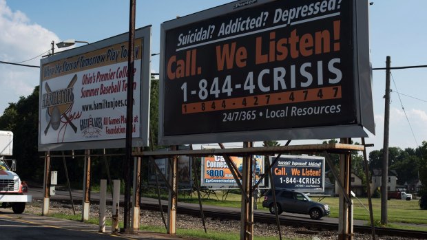 Billboards stand along the side of the road and in a parking lot advertising a local crisis hotline in Hamilton, Ohio. 