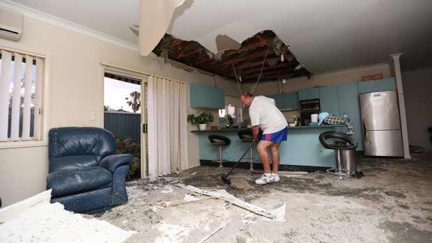 Frank Partlic cleans up rubble in his home.
