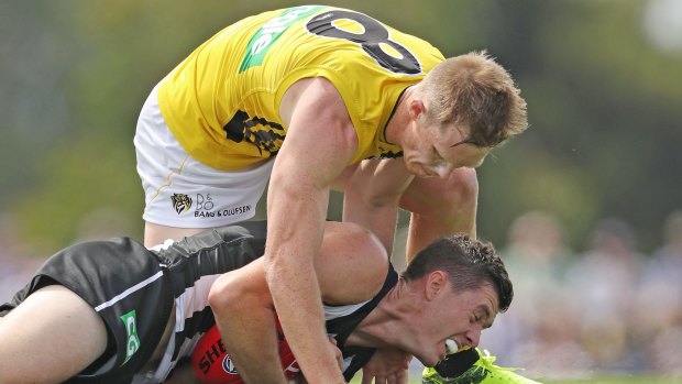 Henry Schade of the Magpies is tackled by Jack Riewoldt.