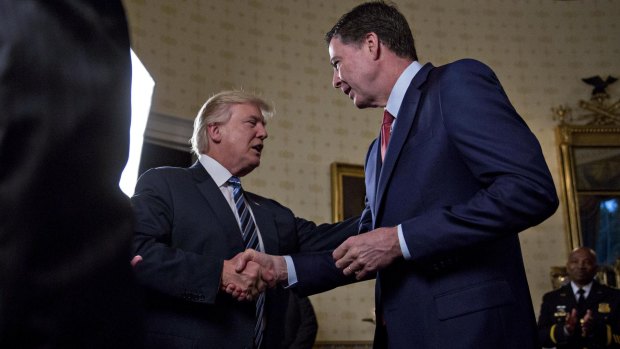 President Donald Trump greets then-FBI director James Comey with a handshake, before pulling him in for a hug. 