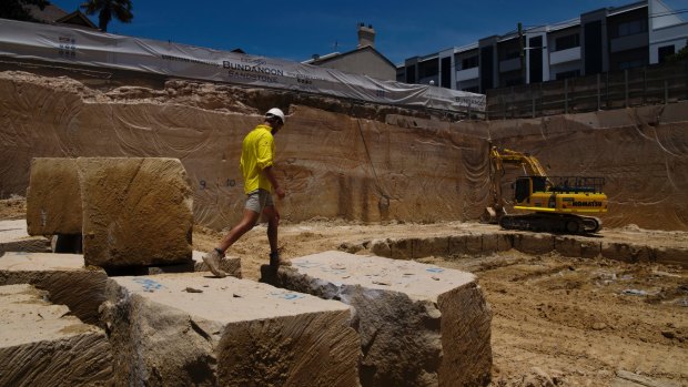 A worker traverses the yellow block boulders at the Bundanoon Sandstone quarry in Harris Street, Pyrmont.