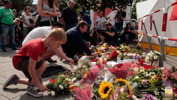 People lay flowers and candles outside the OEZ shopping centre the day after a shooting spree.