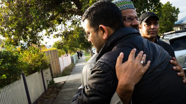 Imam Mohammad Ramzan embraces members of the Islamic community outside the burnt-out mosque.