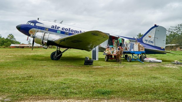 An old Douglas DC-3 propeller plane loaded from a donkey carriage in Colombia