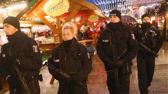 Heavily armed police walk through the reopened Breitscheidplatz Christmas market, the site of the deadly attack.