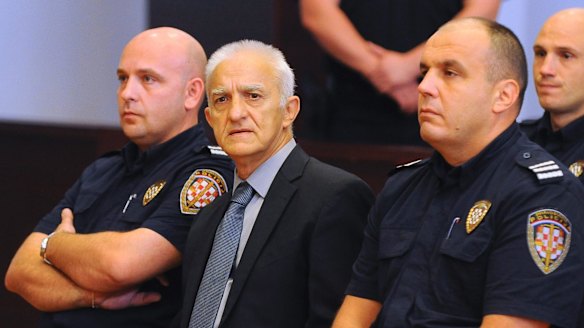 Dragan Vasiljkovic, center, sits between two guards in a courtroom at the beginning of his trial.
