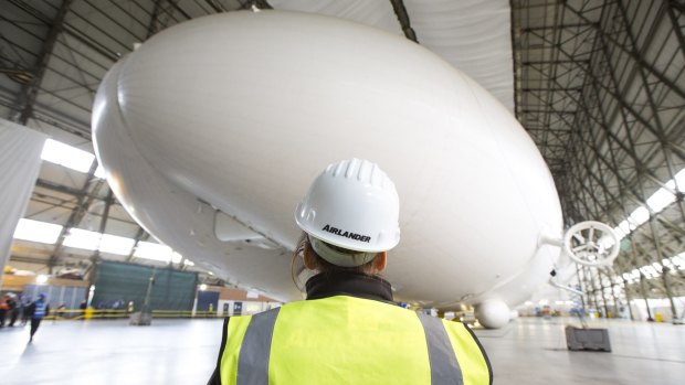 A worker stands in front of the Airlander 10 hybrid airship.