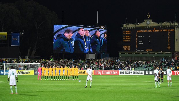 Socceroos players observe a minute's silence before the qualifier in Adelaide on Thursday as Saudi Arabia players continue their warm-up. 