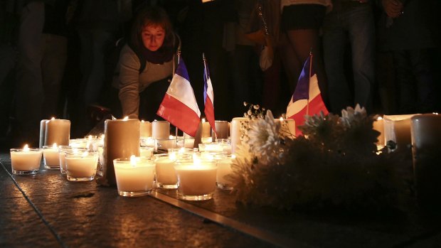 A woman places a candle during a Sydney vigil for the victims of the Bastille Day tragedy in Nice.