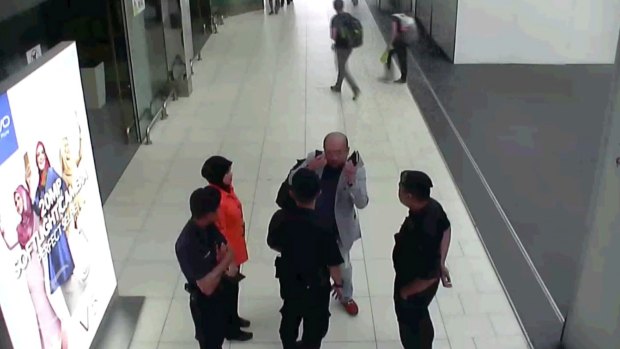 Kim Jong-nam, in grey, gestures towards his face while talking to airport security shortly before his death.