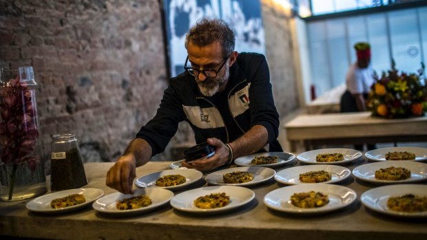 Italian chef Massimo Bottura sprinkles spices onto Mediterranean-style couscous before it is served to the guests at Refettorio Gastromotiva.