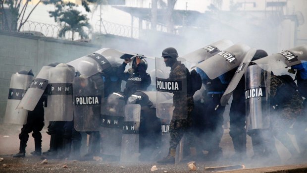 Police stand amid tear gas as they clash with supporters of opposition presidential candidate Salvador Nasralla near the institute where election ballots are stored in Tegucigalpa, Honduras.