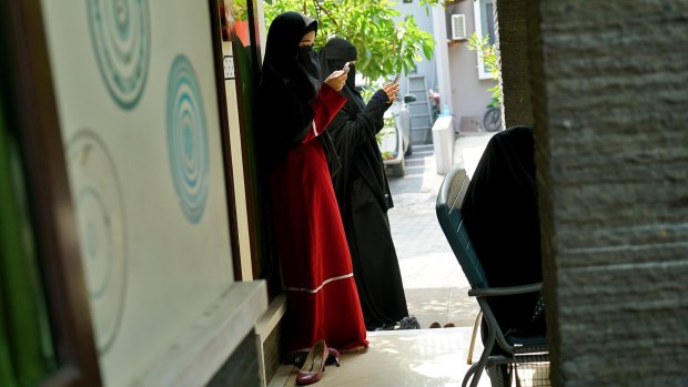 Niqab Squad members check their phones outside a gathering in Bogor, Indonesia.