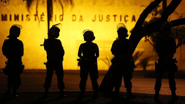 Police keep watch outside the Justice Ministry during protests as a special session is being held in the Brazilian Senate.