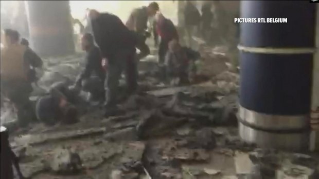 People receive treatment in the debris-strewn terminal at Brussels Airport after the airport bombing.