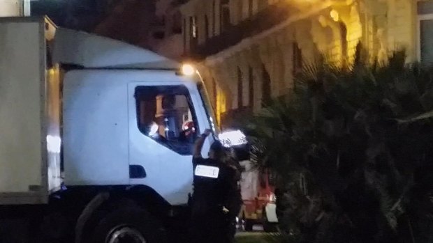 Police shine a light in the cab of a truck which ploughed into a crowd in Nice, killing 84. 