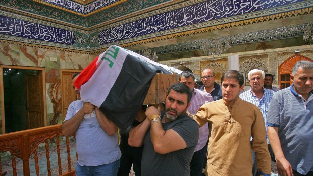 Mourners carry the Iraqi flag-draped coffin of Talib Hassan, 35, killed in the Karada attack. 
