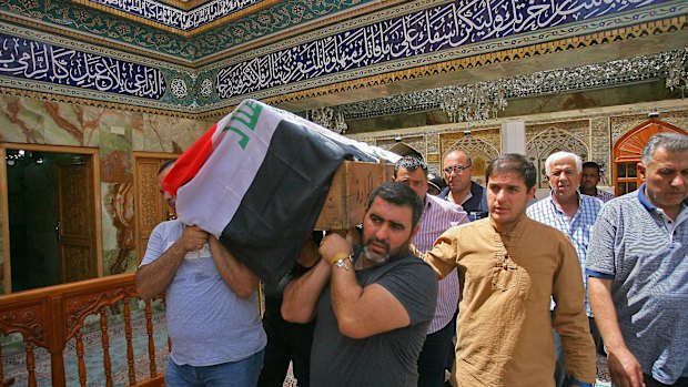 Mourners carry the Iraqi flag-draped coffin of Talib Hassan, 35, killed in the Karada attack. 