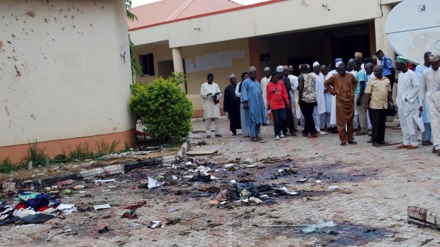 Journalists and other government officials gather at the scene of a bomb blast at Sabon Gari in Nigeria on July 7.