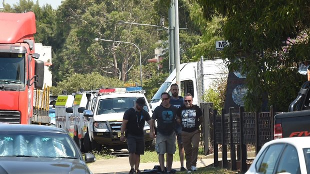 Peter Williams is handcuffed by police and led from the scene during the standoff with police at Ingleburn.