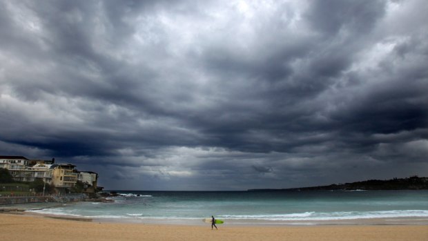 A lone surfer on Bondi Beach Christmas eve as ominous clouds signal the approaching weather system that will bring storms and dangerous surf conditions to Sydney.
